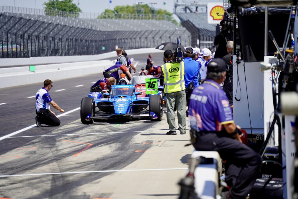 Indy car in the pits as the crew works on the car