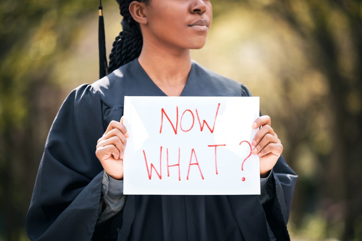 college graduate with a sign saying "now what?"